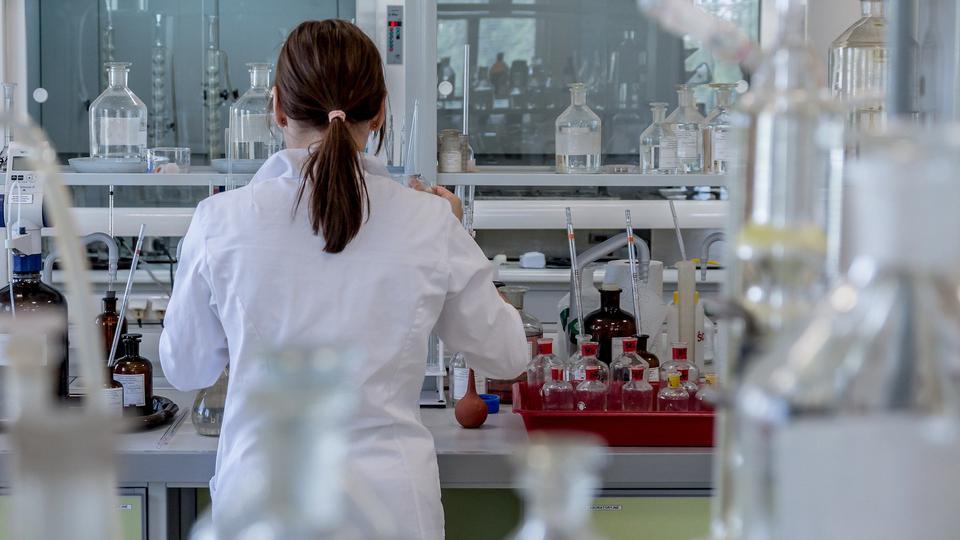 A woman working in a laboratory, turning her back to the camera